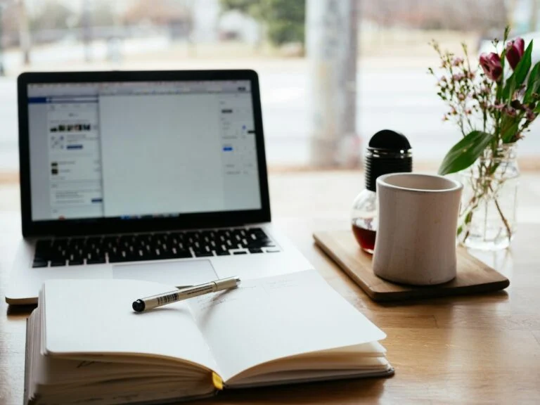 Laptop, open notebook, pen and coffee on a wooden table