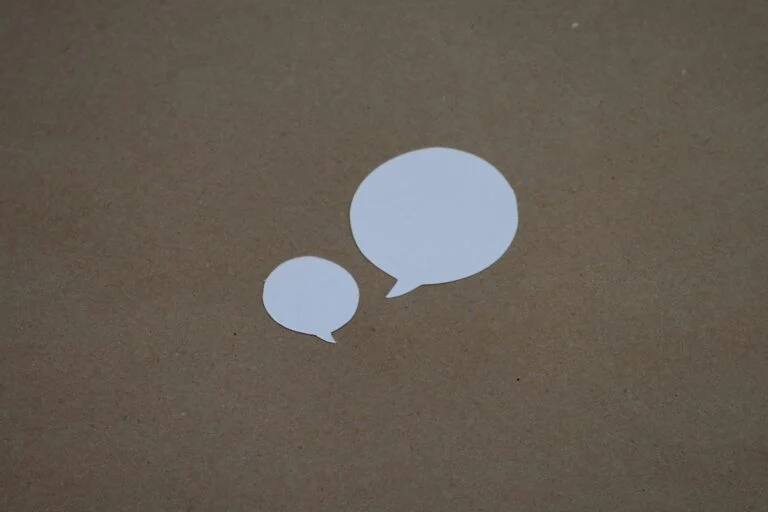 Two paper speech bubbles on a brown background