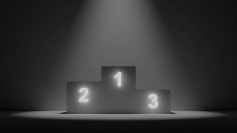 Empty winners' podium numbered one, two and three under a spotlight