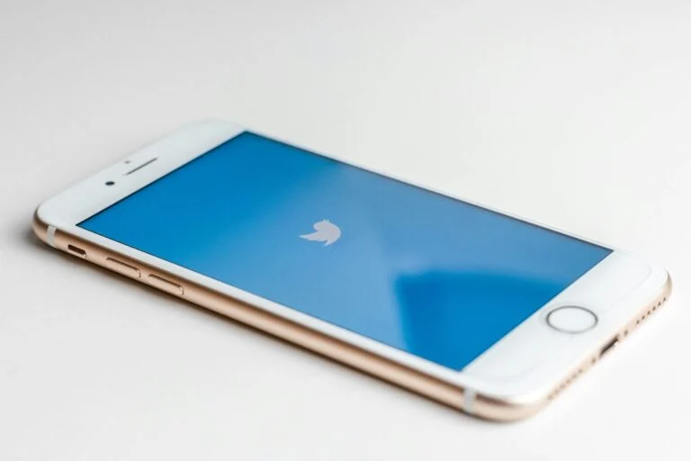 Phone lying on a white surface showing the Twitter logo