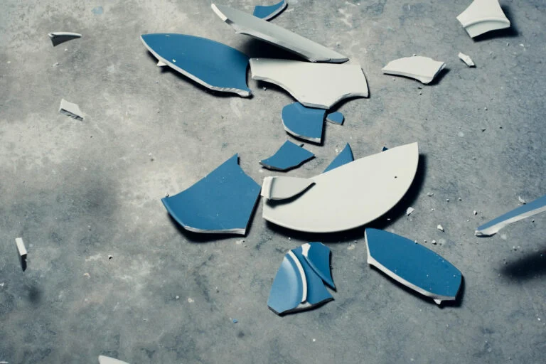 Smashed blue and white plate on a concrete floor