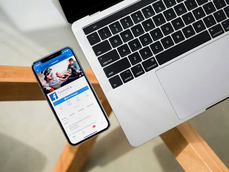 Phone showing a Facebook feed propped against a laptop
