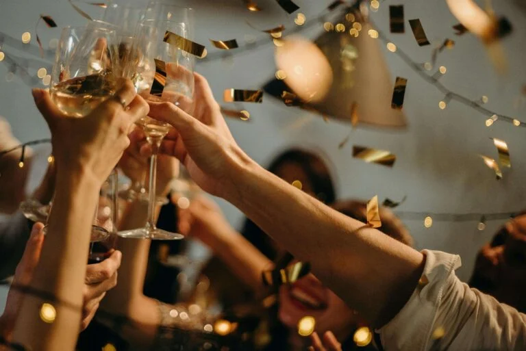 Hands raising champagne glasses amid falling confetti