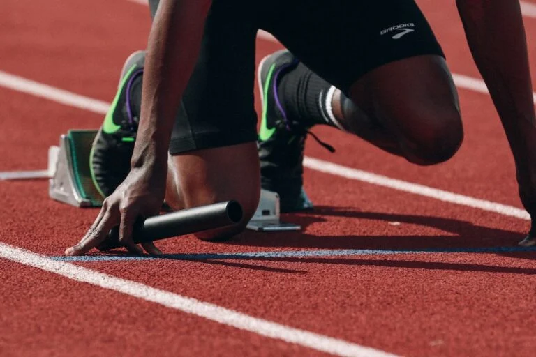 Sprinter crouched in the starting blocks on a red running track
