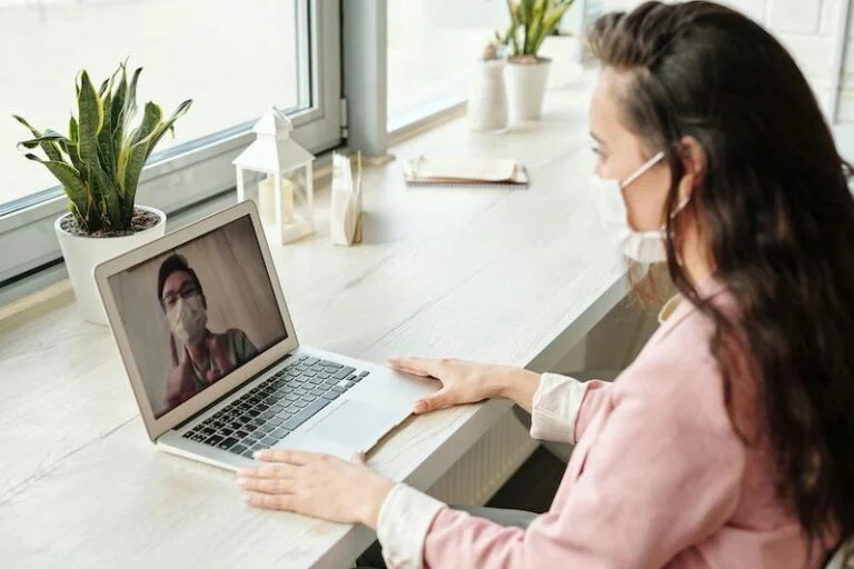 Woman in a face mask on a video call at her laptop