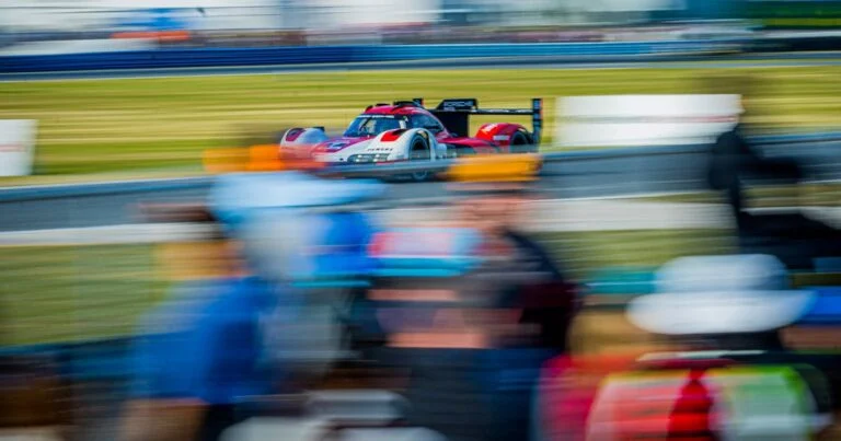 Race car blurred with motion as it passes a pit crew