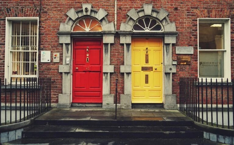 A red door and a yellow door side by side on a brick building