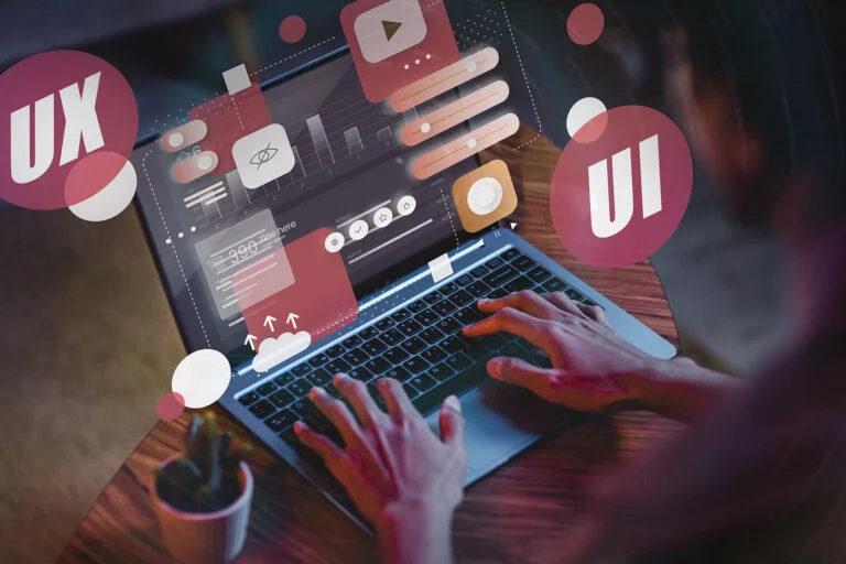 Hands at a laptop surrounded by glowing UX and UI bubbles