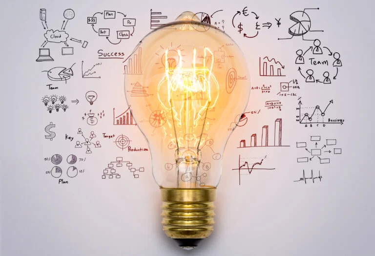 Lit light bulb surrounded by hand-drawn charts and diagrams