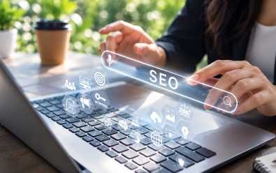 A hand reaching toward a search bar surrounded by SEO icons above a laptop